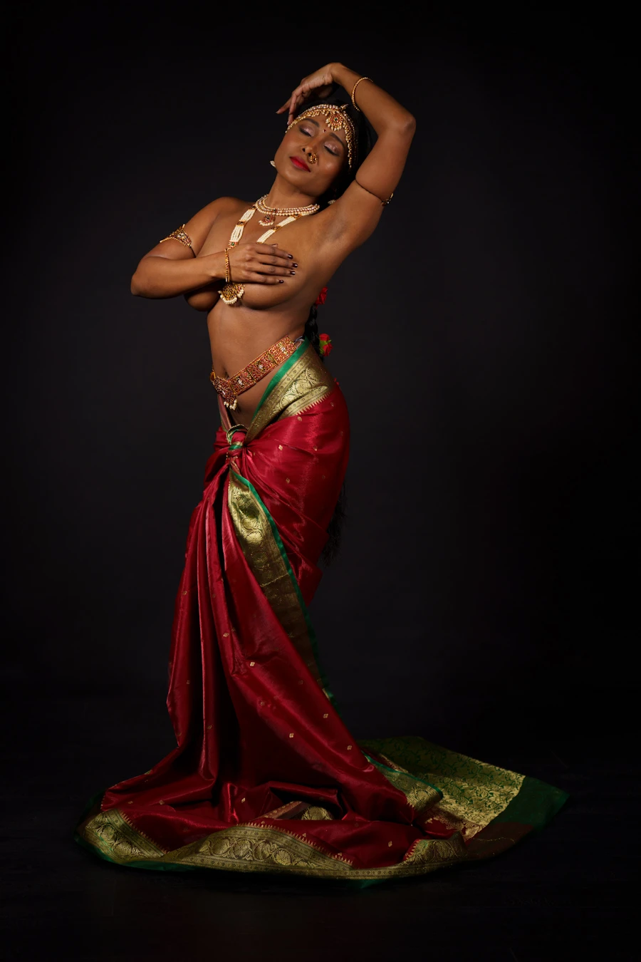 Desi model posing topless wearing havy jewellery and hiding her big tits with her hands while wearing a red saree on her hips