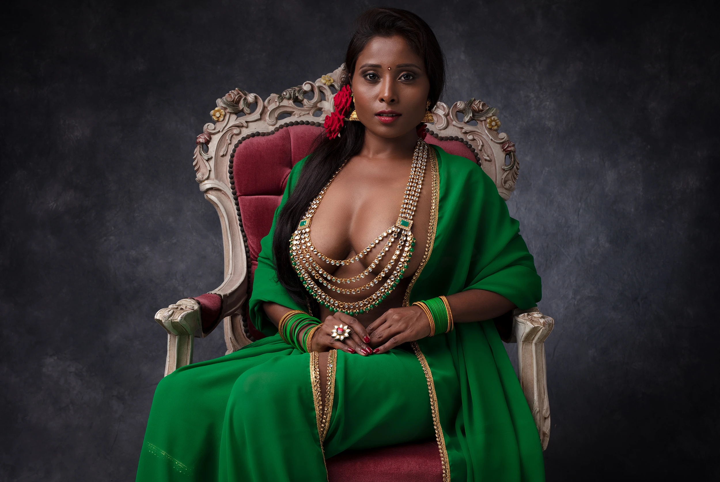 Desi dusky model posing topless wearing large necklace hiding her big tits with it while wearing a green saree and sitting on a chair