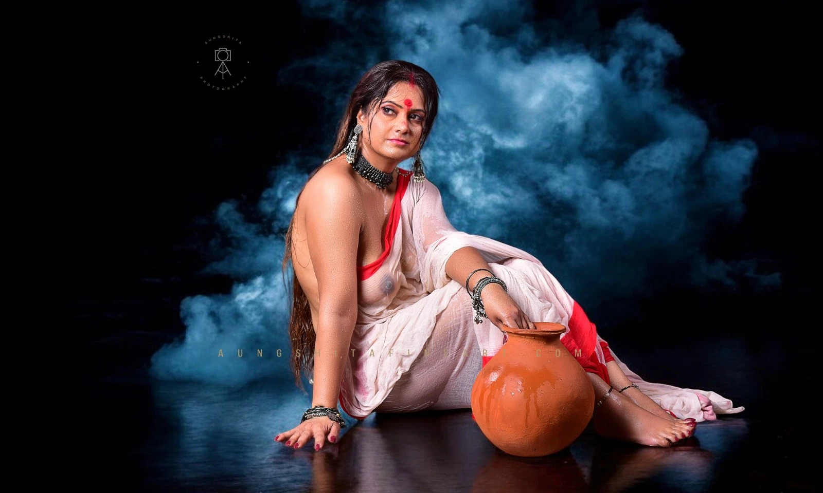Desi MILF shows her big boobs in a wet white transparent braless saree and sitting down with a clay pot