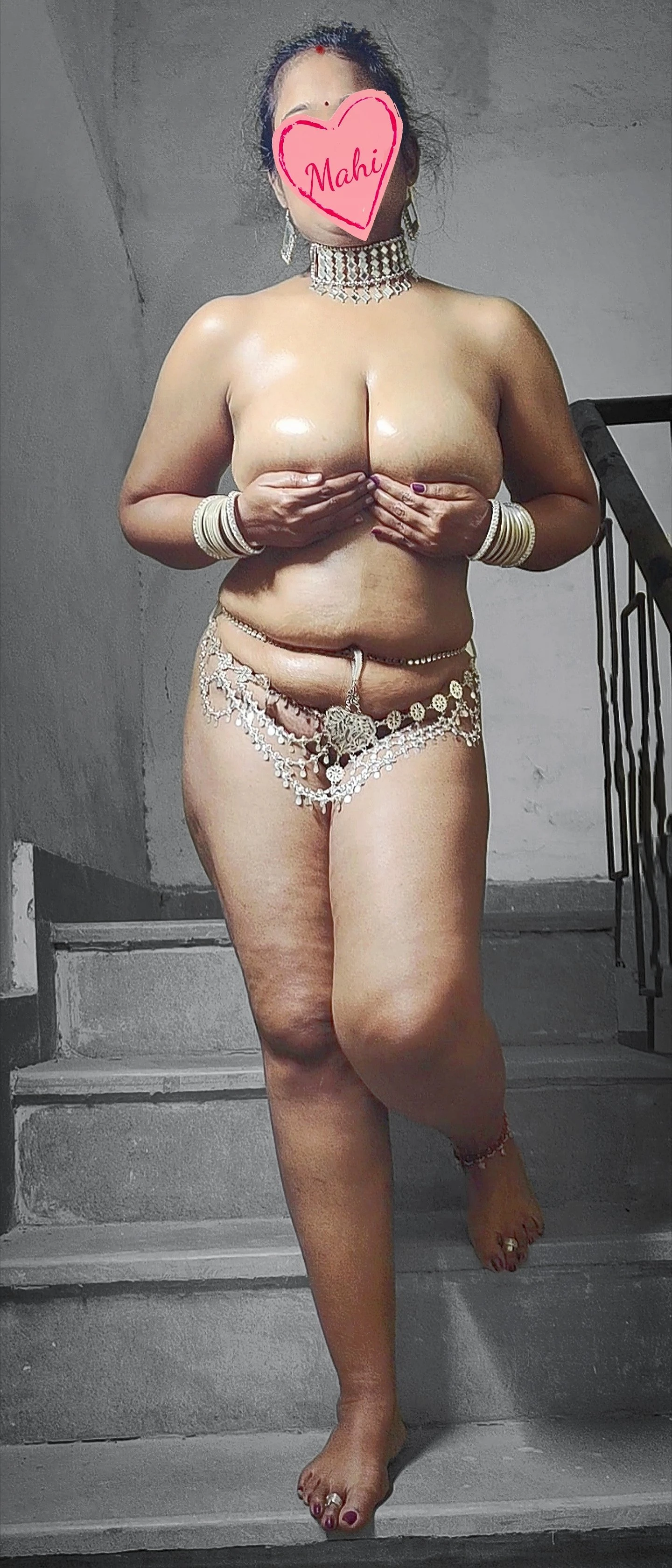Nude Indian wife covering her huge melons with hands and pussy with belly chain and posing in the nude on stairs