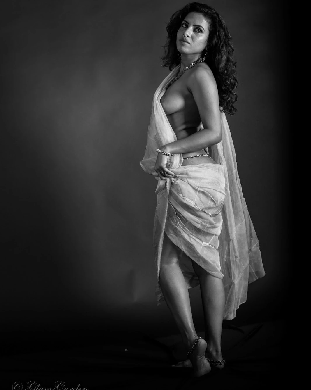 Desi MILF wearing thin belly chain shows her big boobs from the side while posing in a braless saree