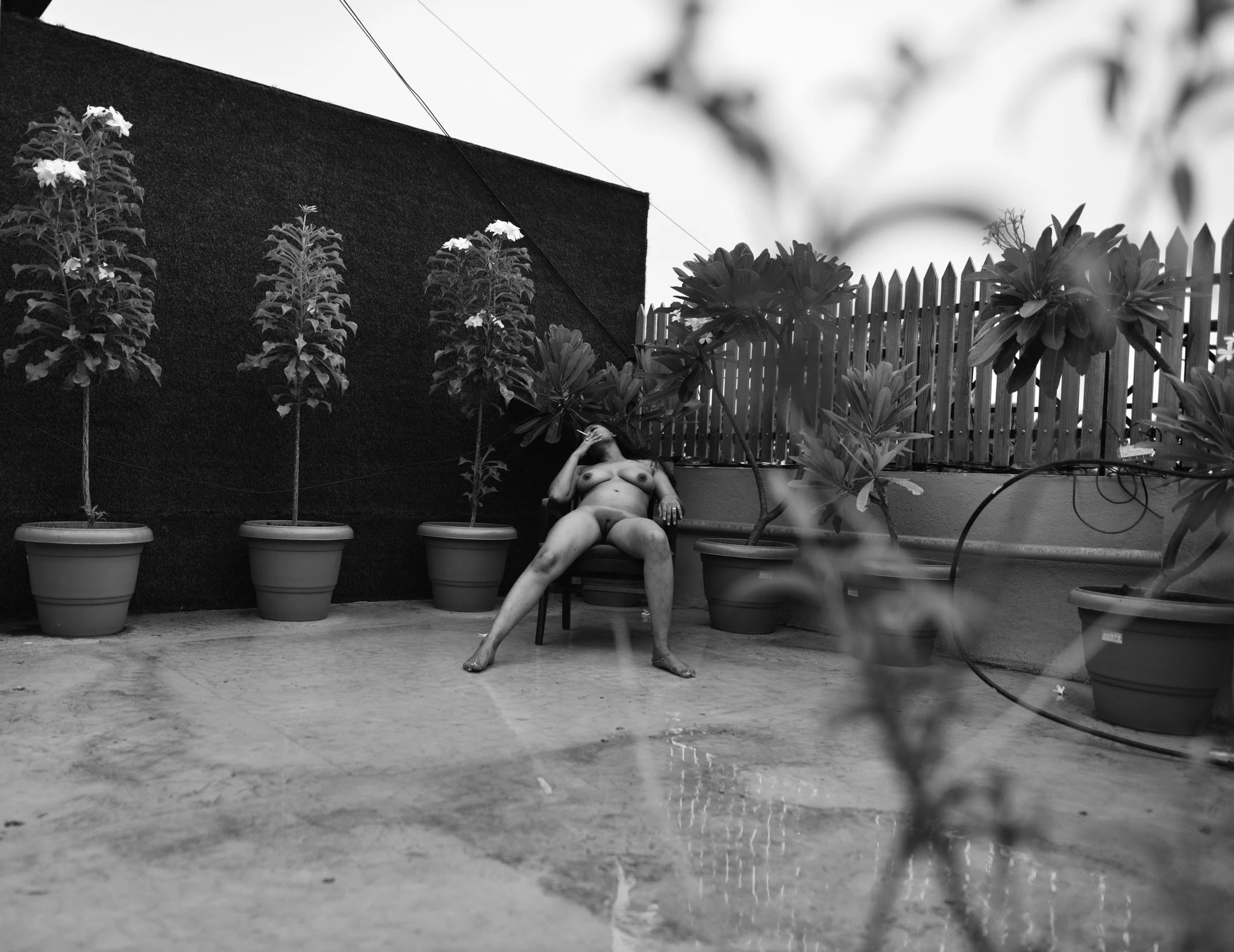 Bangladeshi MILF model sitting completely nude on a chair in open terrace and smoking