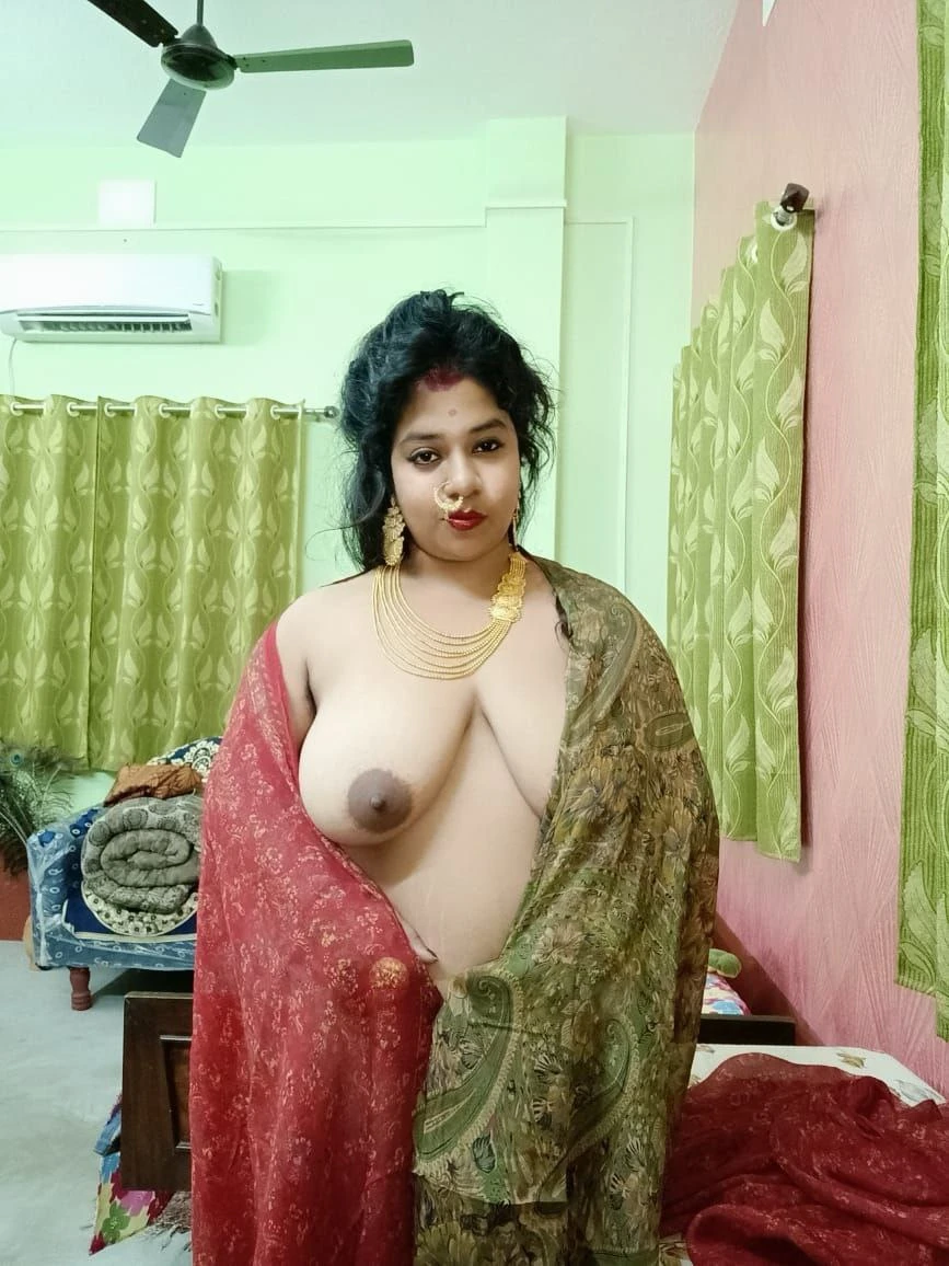 Topless Desi MILF wearing gold necklace and nose ring cups shows one of her big tits while covering herself with a blue and red saree