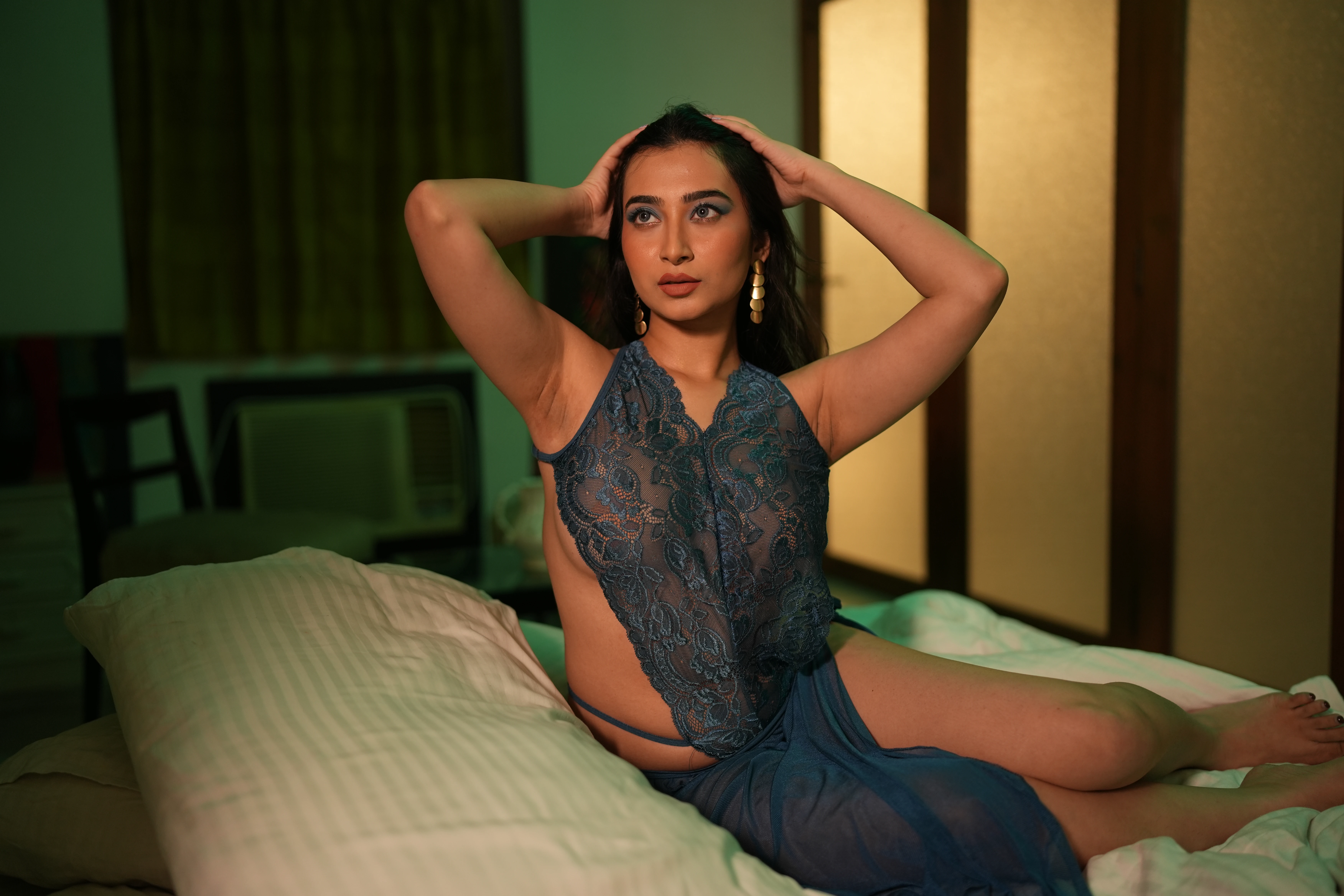 Desi MILF model shows her big breasts confined in a dark green lace lingerie while posing with her hands on her head