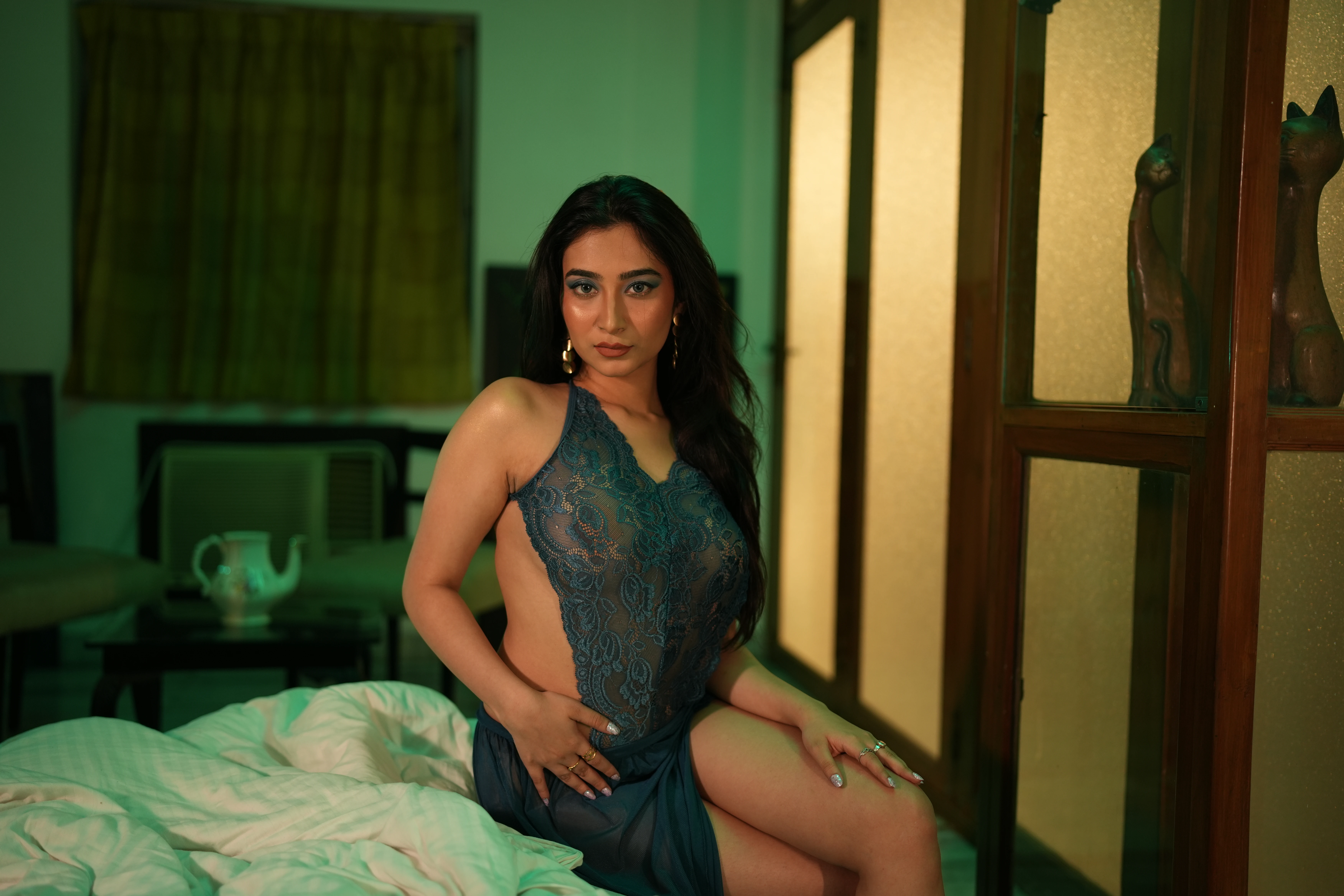 Desi MILF model shows her big breasts confined in a dark green lace lingerie while sitting on bed