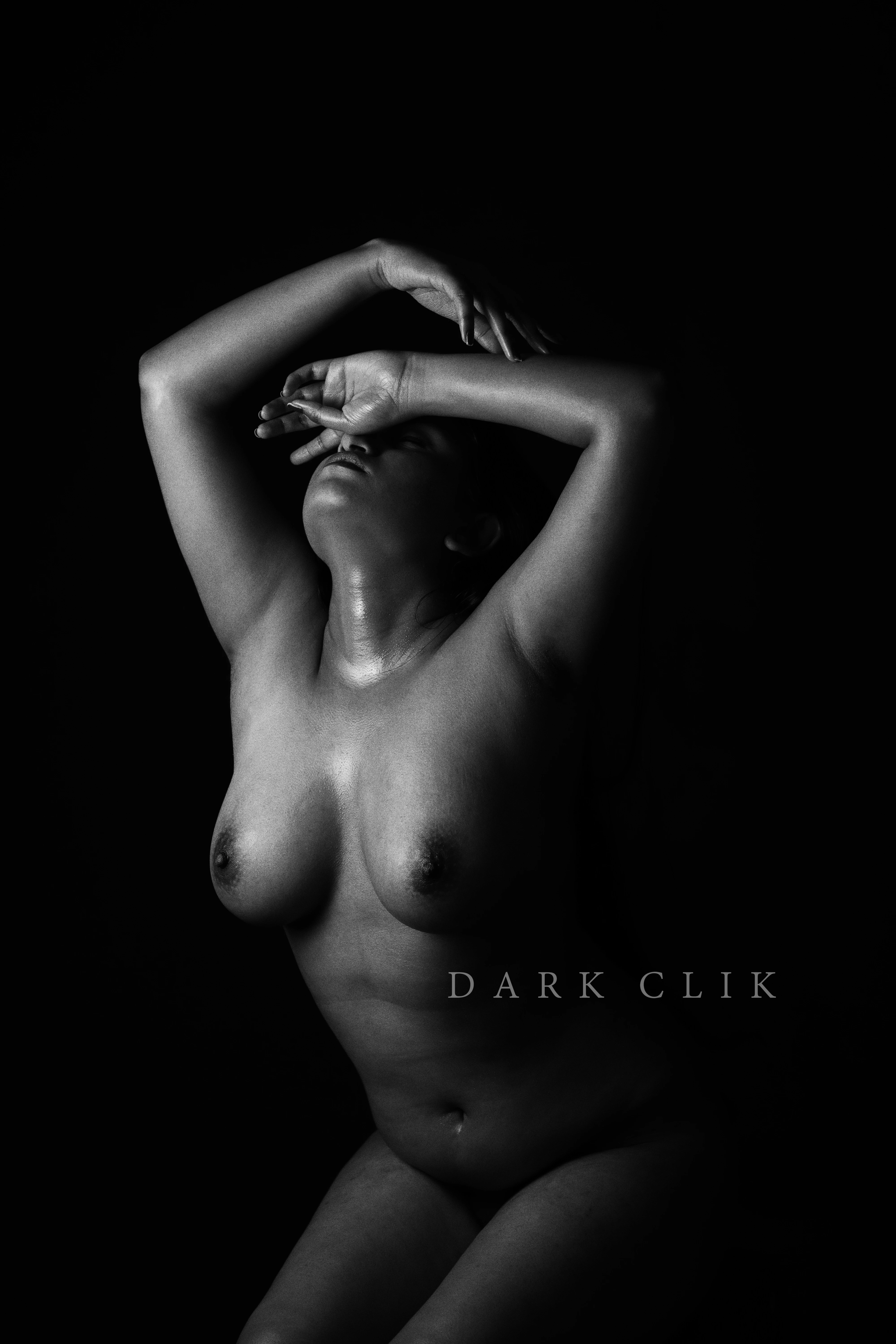 Naked Indian model with raised hand and covering her face revealing her ample boobs and hides her snatch in an erotic photoshoot