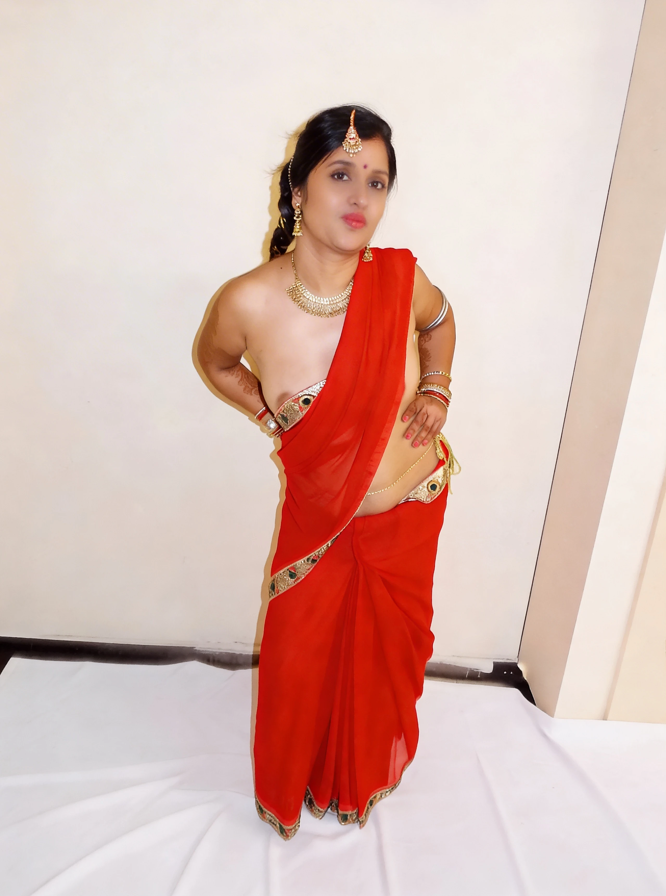 Desi wife wearing a braless orange saree and jewels like a bride and showing glimpses of her boobs