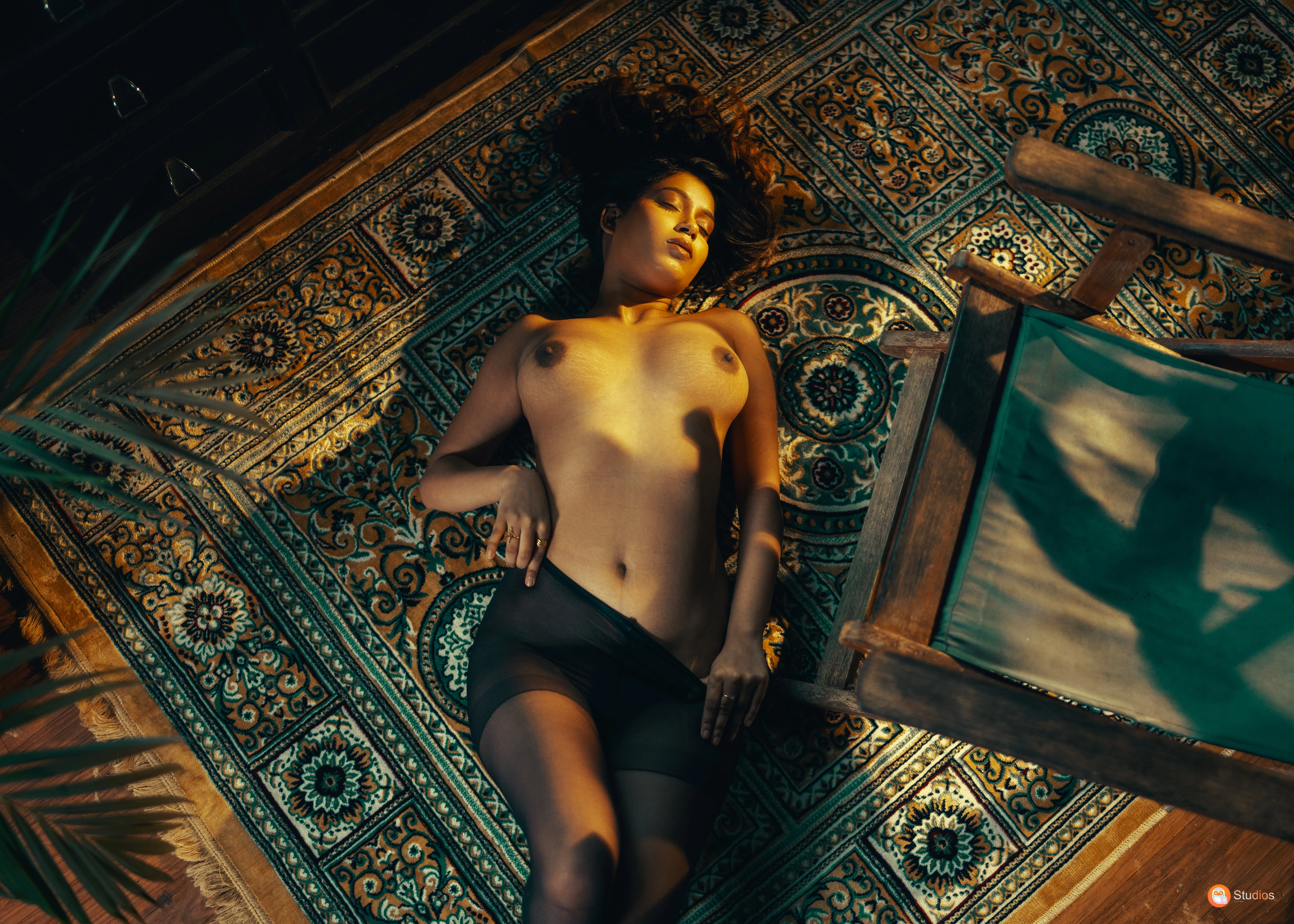 Desi enchantress lying topless on a carpet revealing big boobs and wearing just stockings