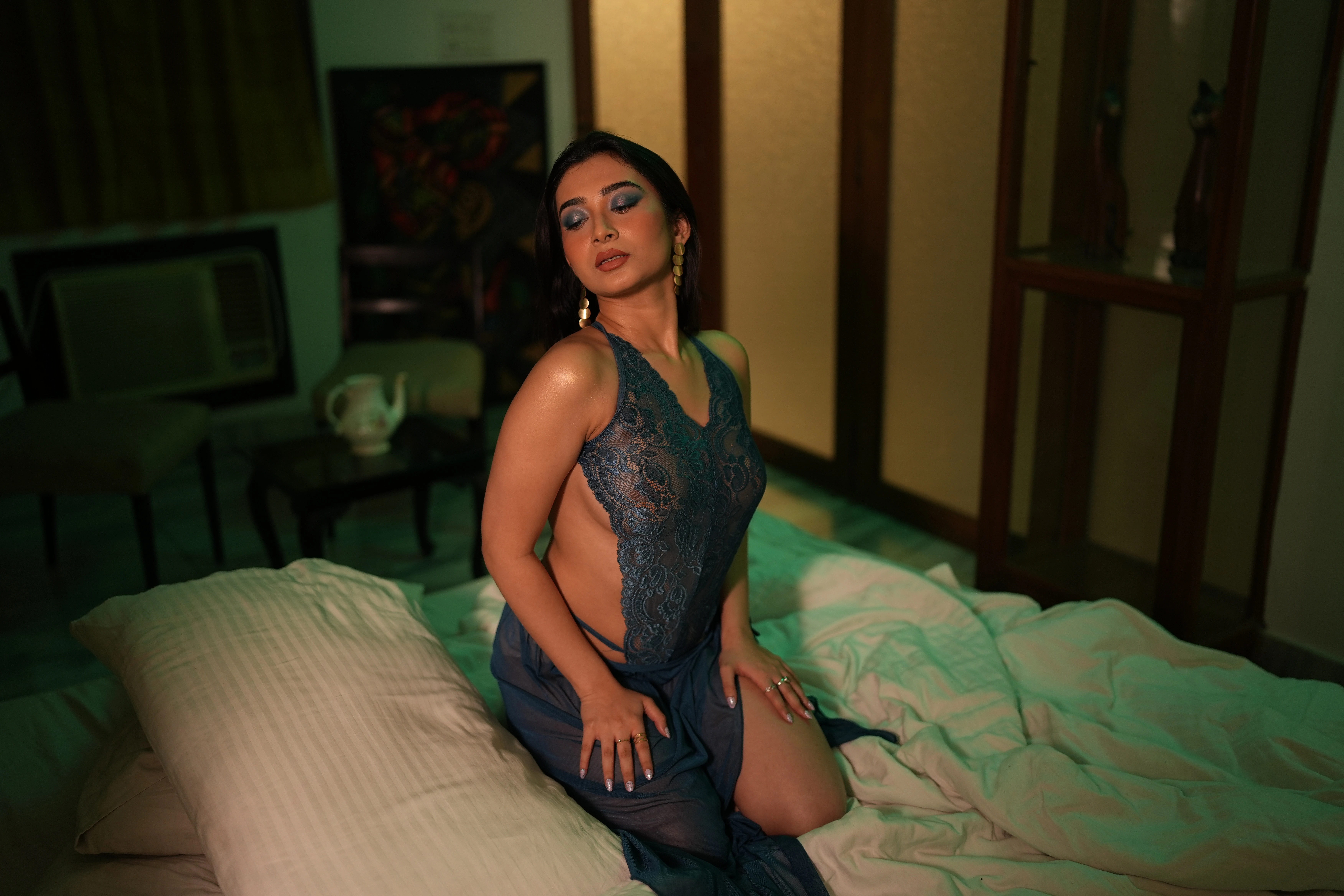 Desi MILF model shows her big tits confined in a dark green lace lingerie while sitting on bed