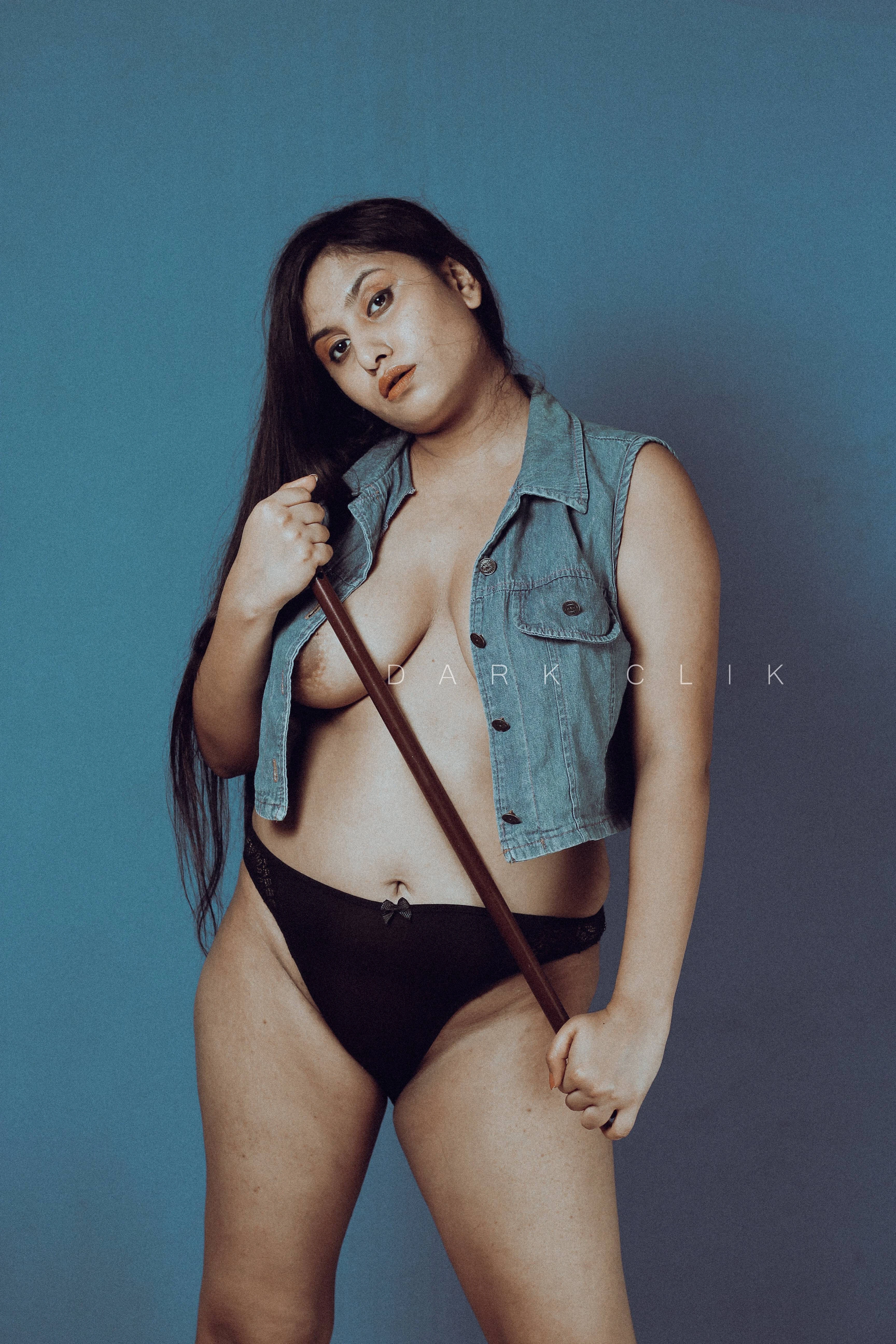 Desi MILF model in an open denim jacket without bra and displaying her big boobs while holding a police lathi