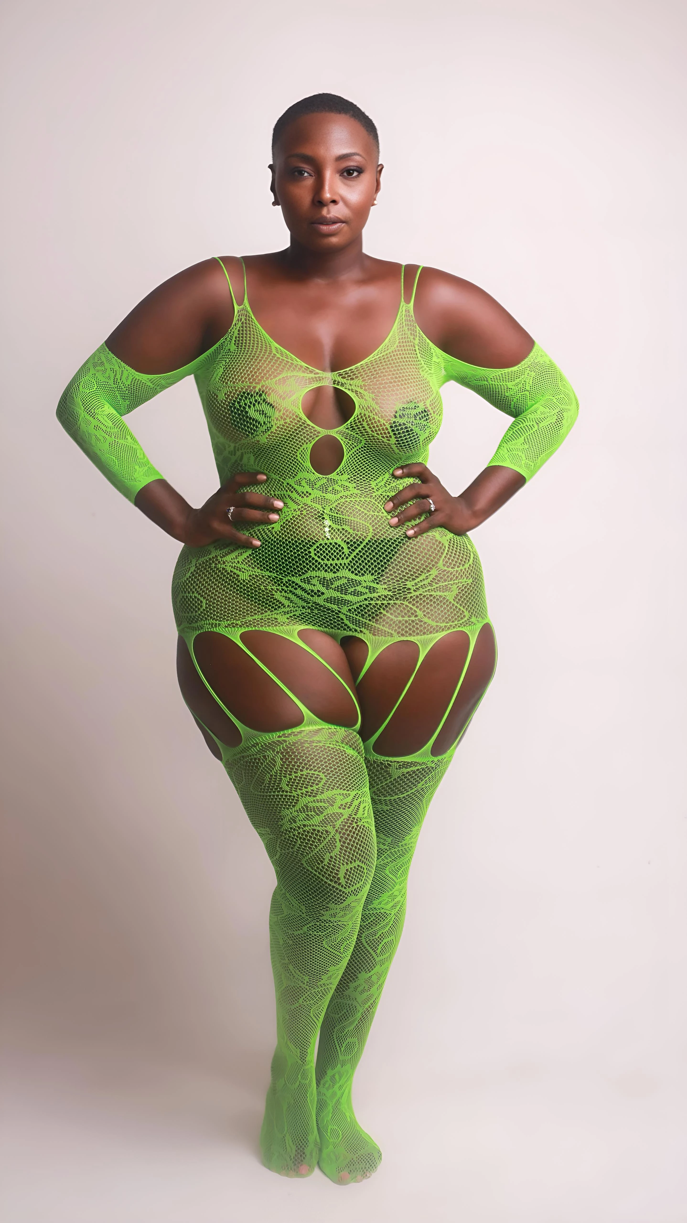 Ebony MILF model tempting with her big boobs with nipple pasties while wearing a green sheer bodysuit lingerie