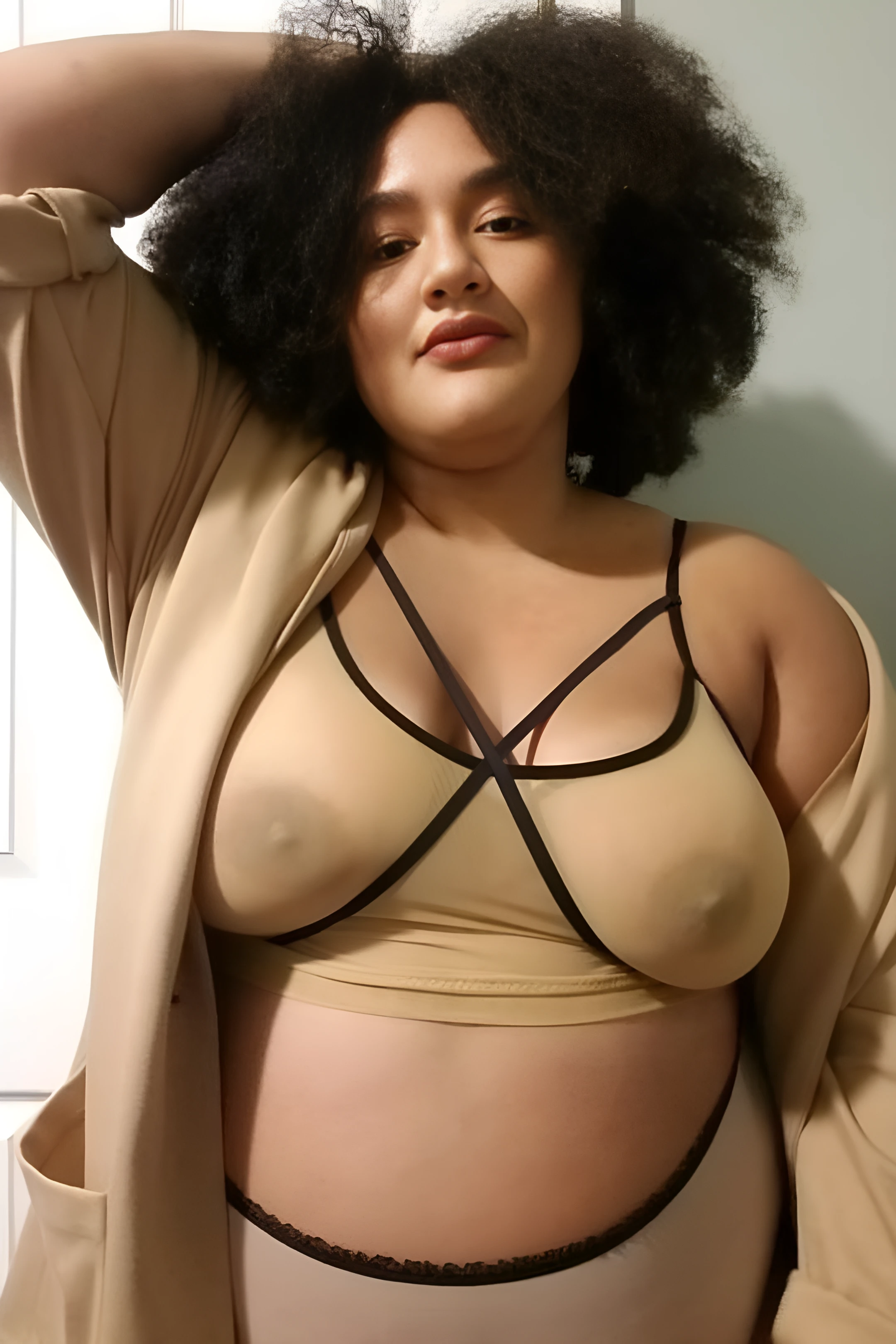 Curly haired lady shows her big boobs through a strappy mesh bra