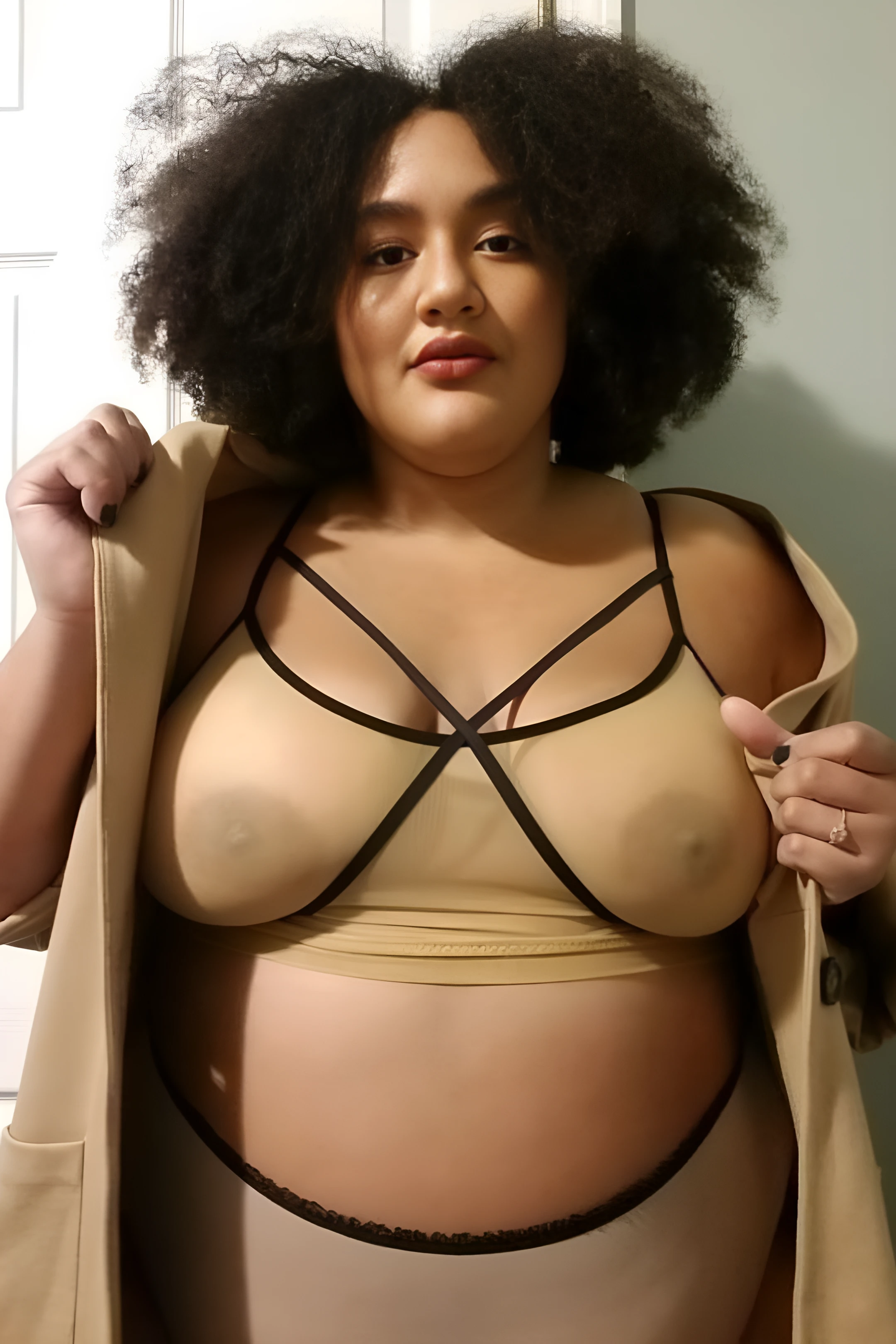 Curly haired lady shows her big tits through a strappy mesh bra