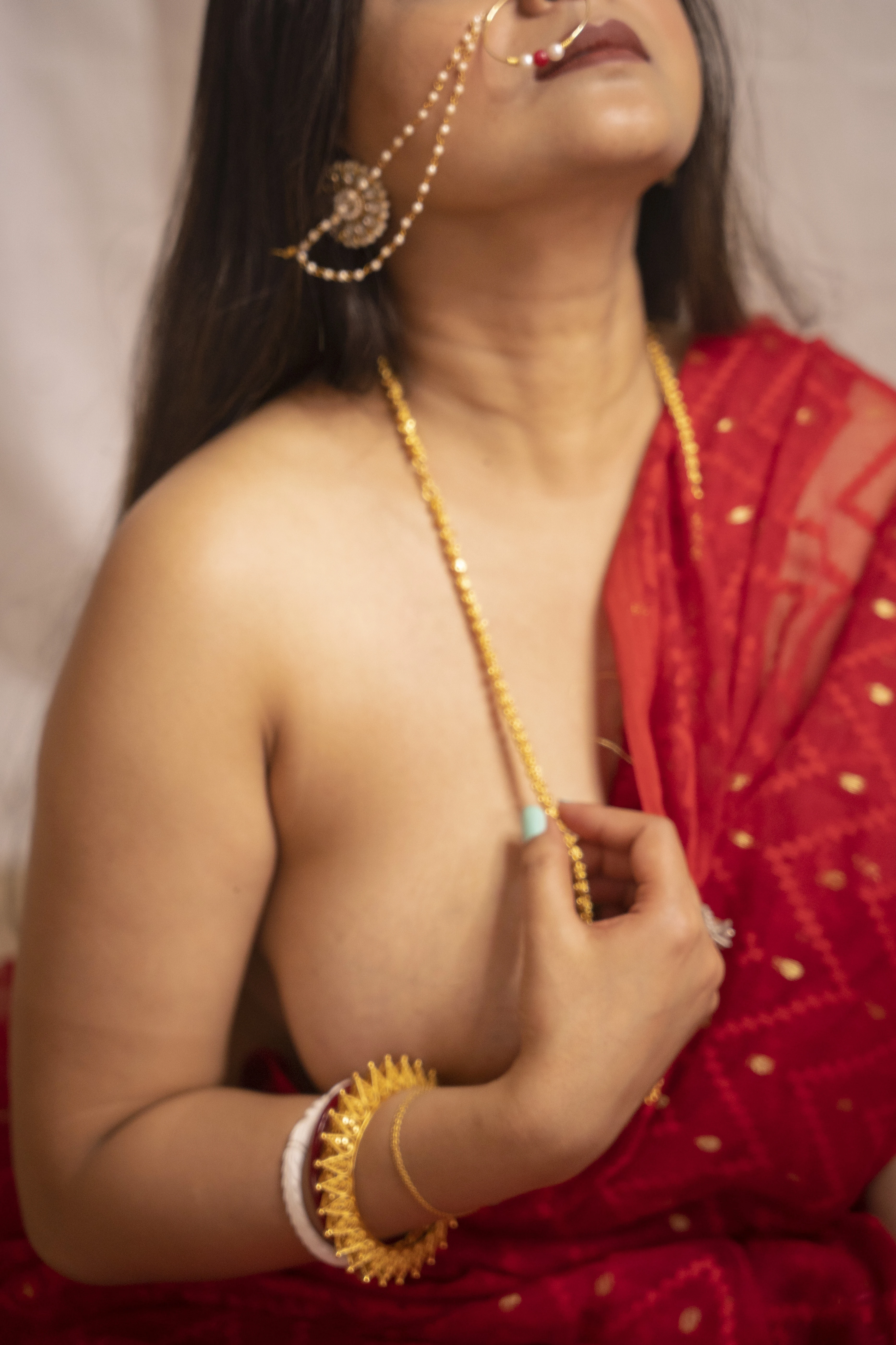 Desi MILF wearing a red braless saree with gold necklace, and nose ring, teases her big boobs