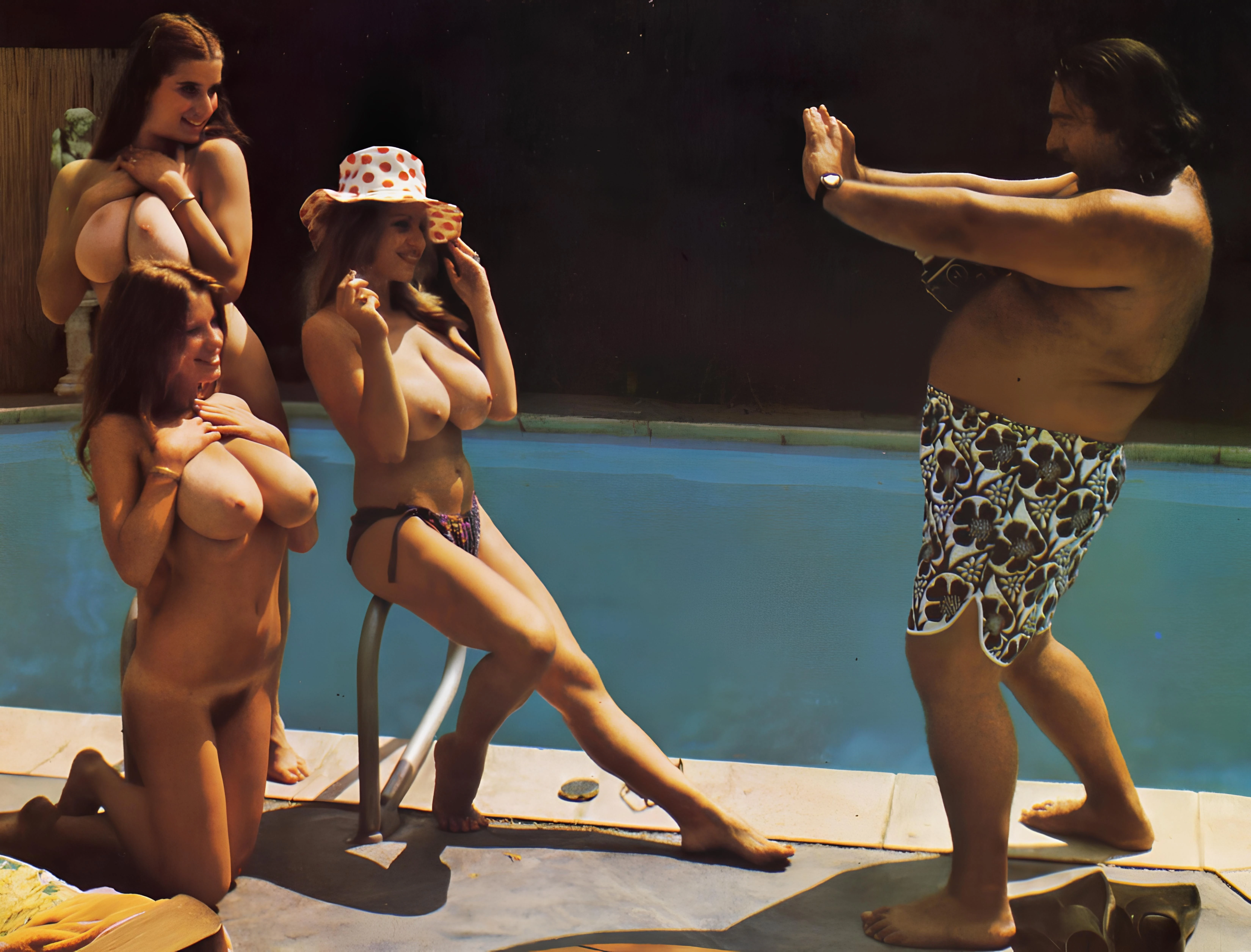 Group of vintage models near a pool and posing nude for a camera