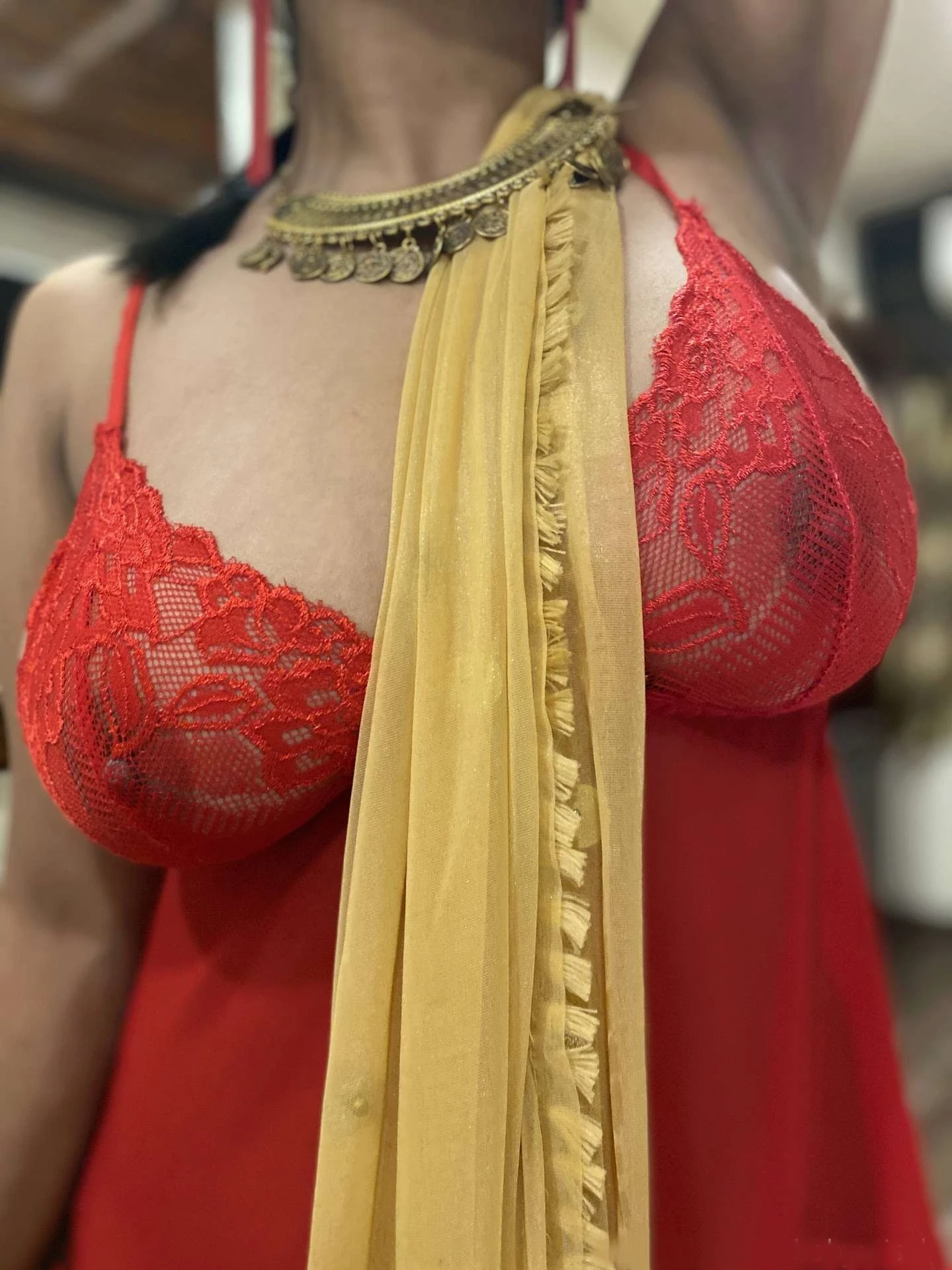 Baby Misaka showing her big boobs inside a red nightgown with lace detailing, complemented by a gold-colored scarf and a bold statement necklace