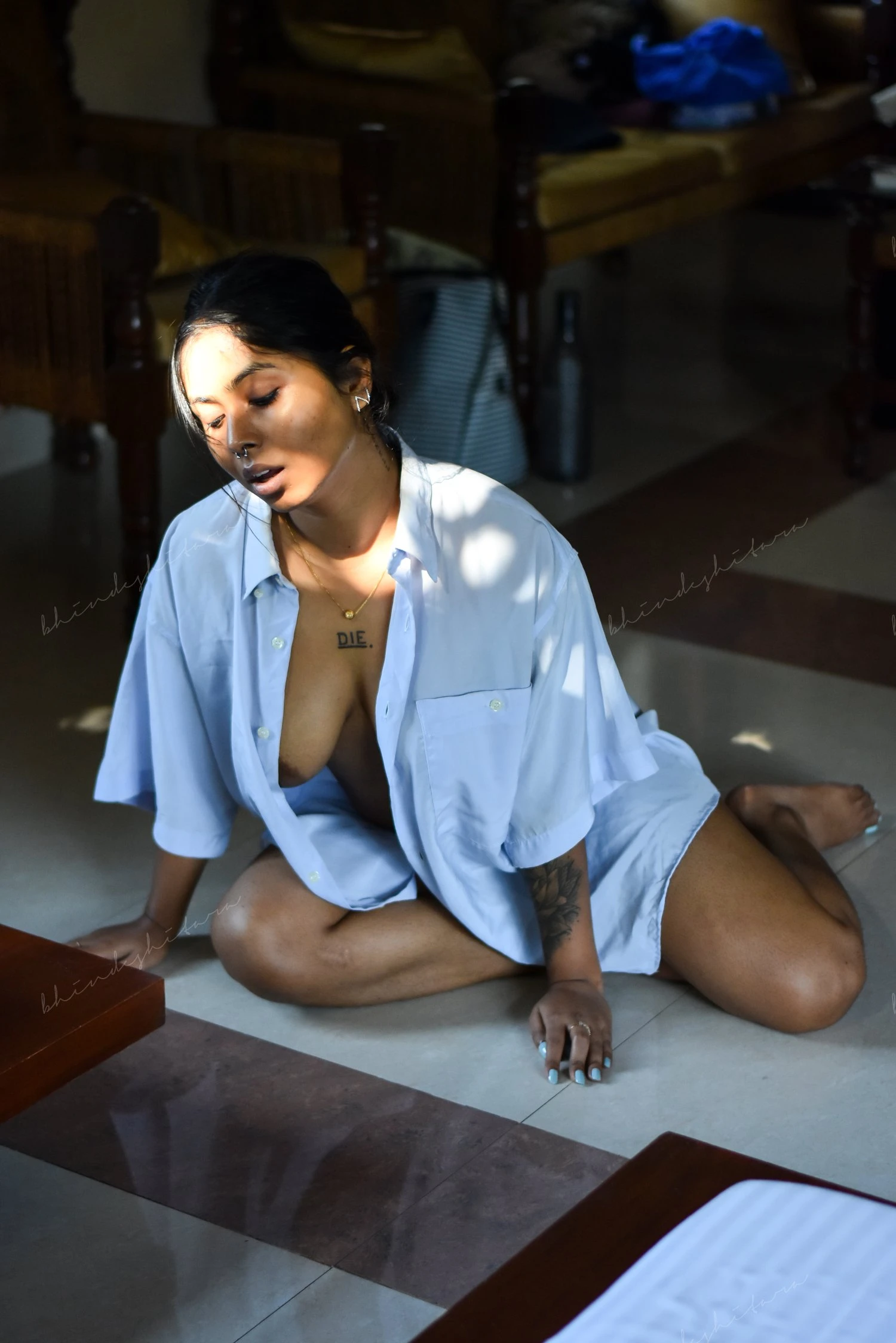 Desi MILF sitting on floor wearing just a blue shirt and partly showing one of her naked boobs and areolas