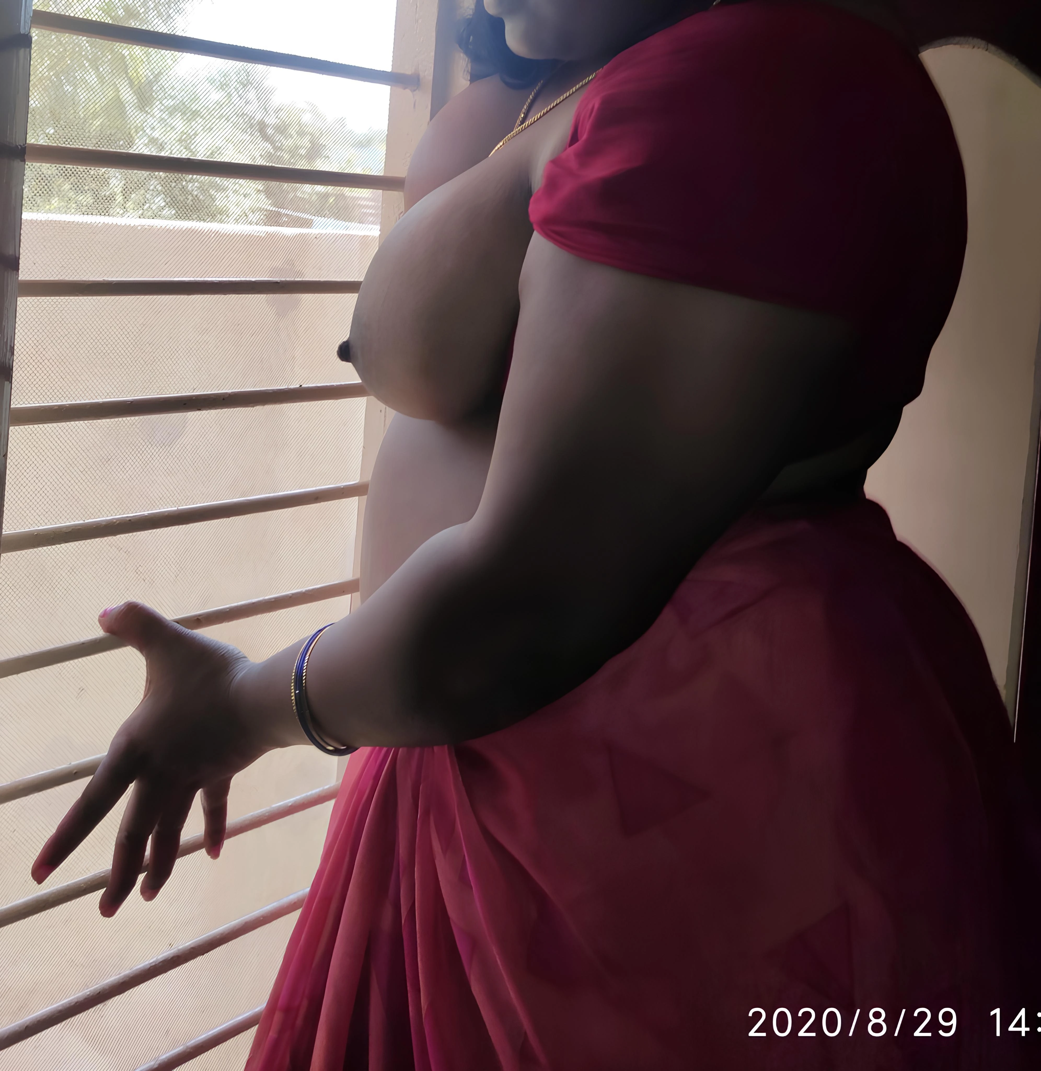 Busty Desi wife pose daringly near an open window and flash her massive melons
