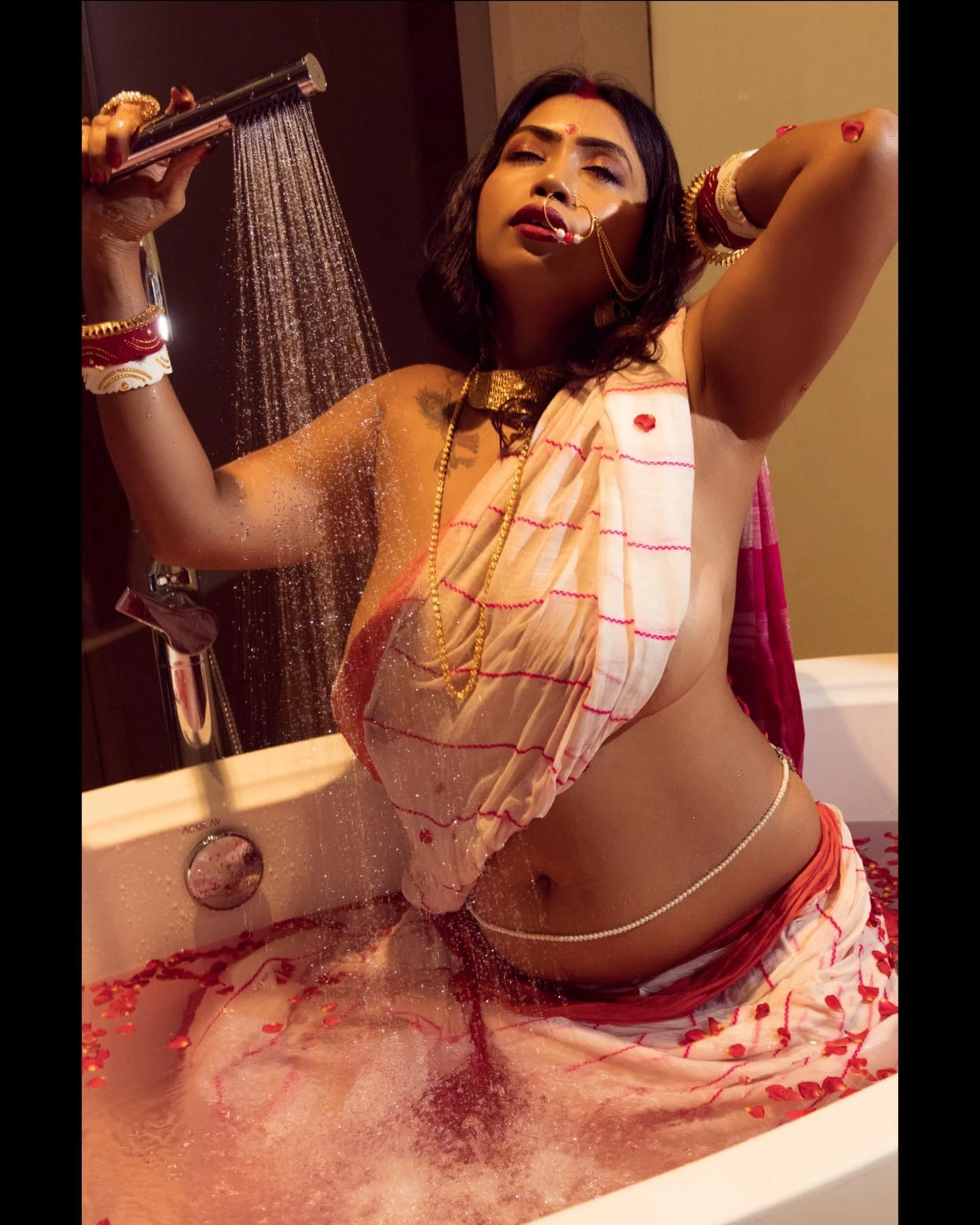 Desi MILF in a braless wet white saree and taking a shower reveals her big tits and pearl body chain while sitting inside a bathtub