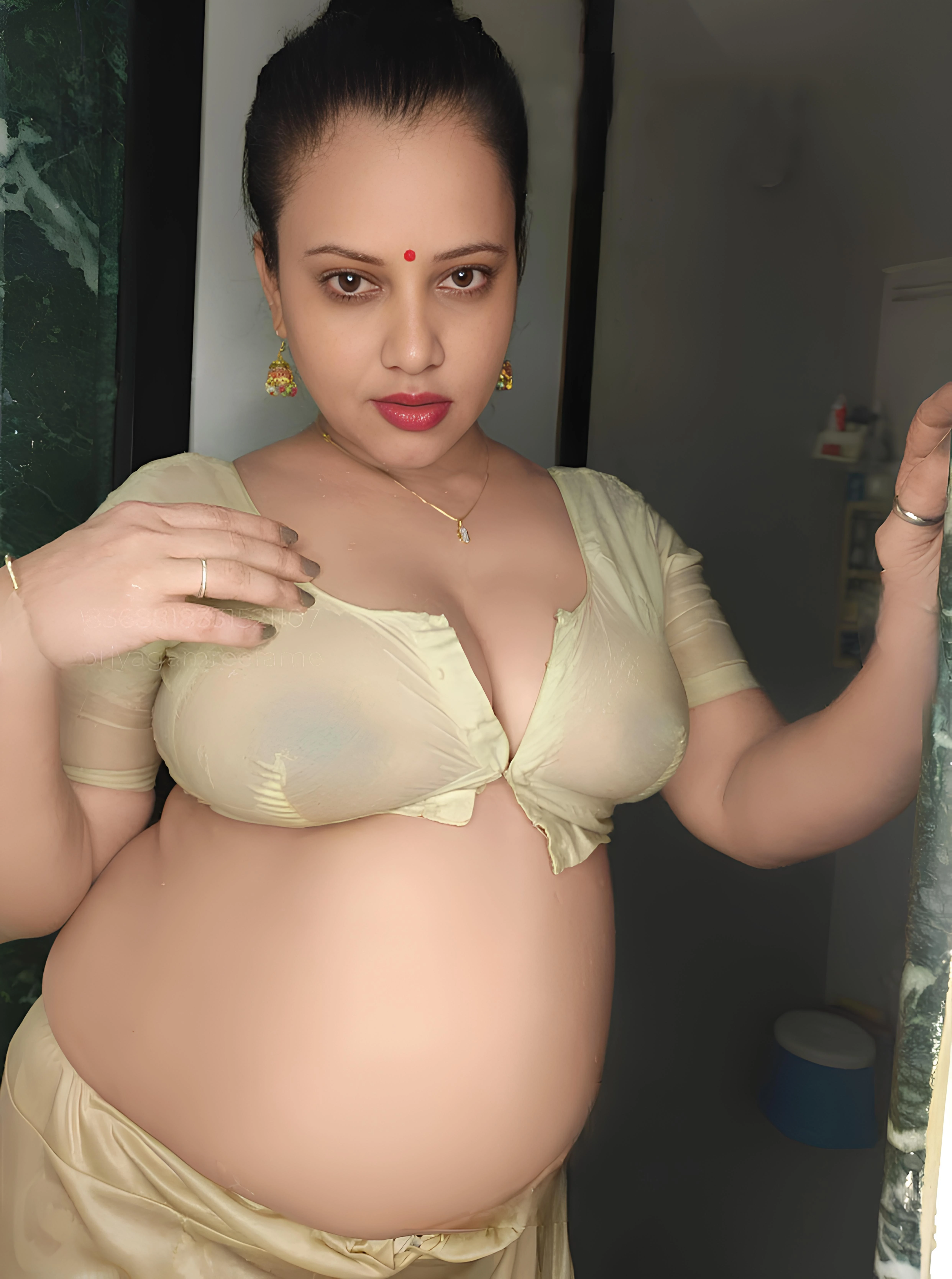 Sexy Desi MILF in a wet, transparent unbuttoned blouse, bares her big boobs and nipples, stands confidently inside the bathroom
