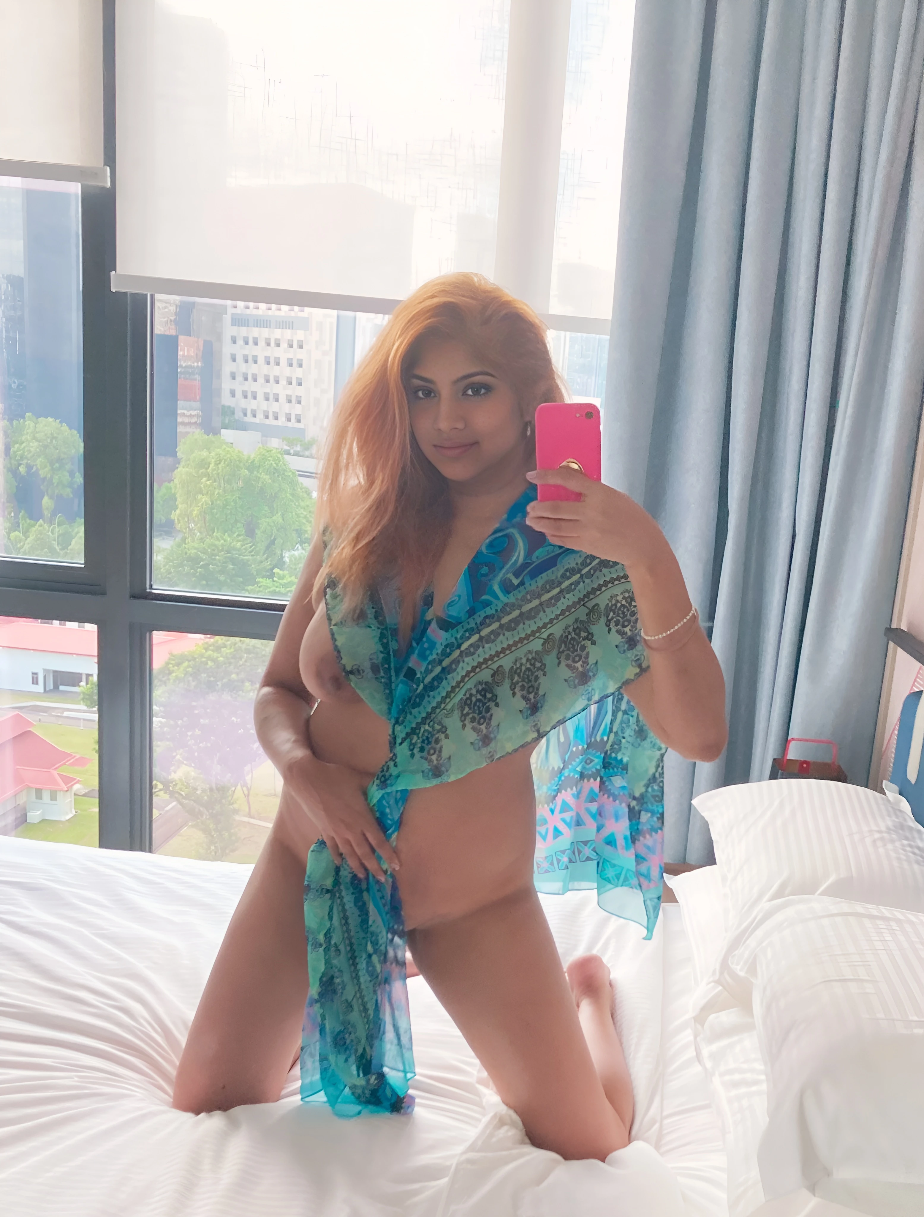 Sultry Desi actress Joshna Fernando kneels almost nude on a hotel bed, a sheer scarf her only cover while taking a selfie