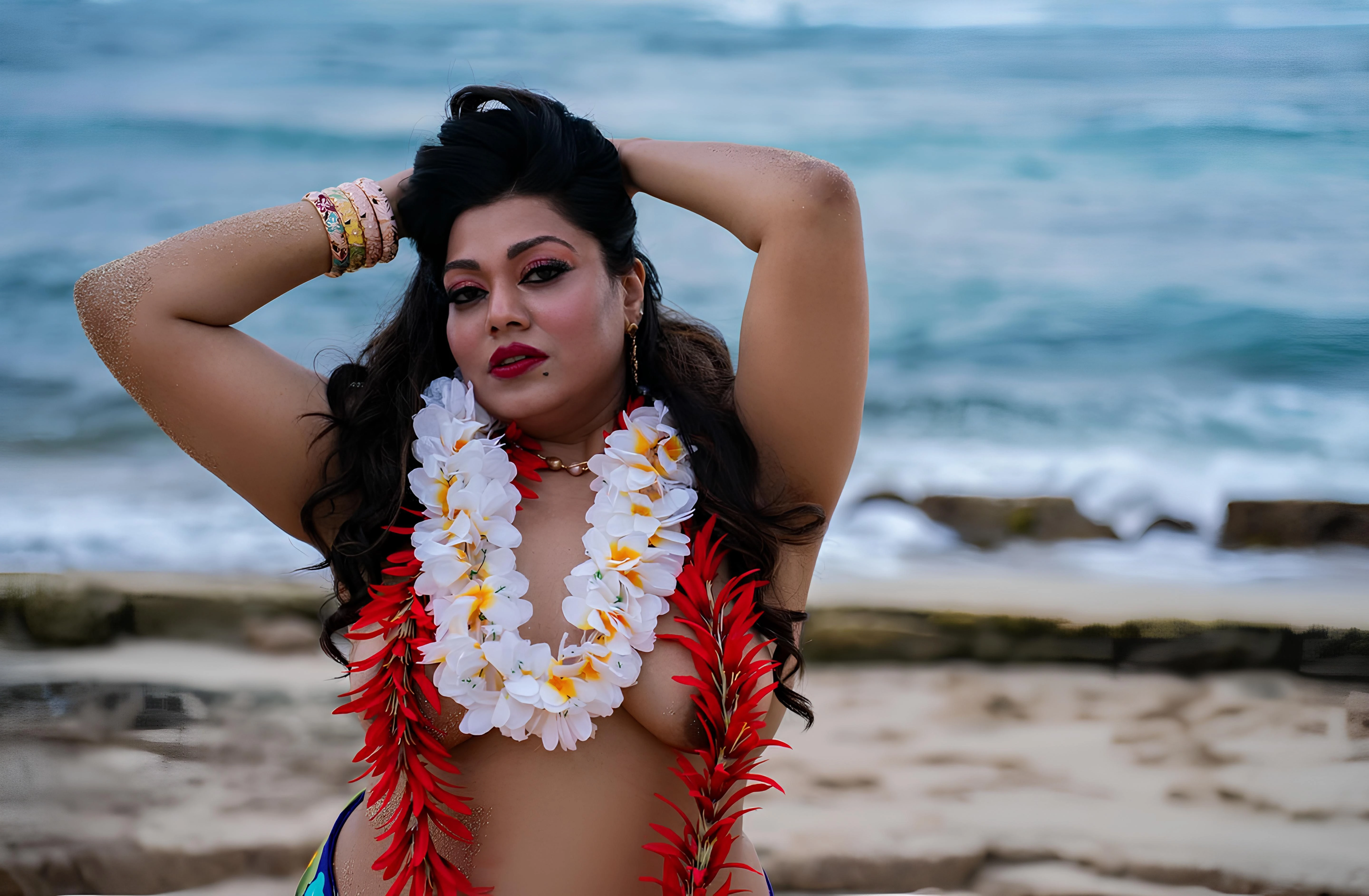 Saroni Roy posing topless with a lei, featuring generous, round breasts on a beach
