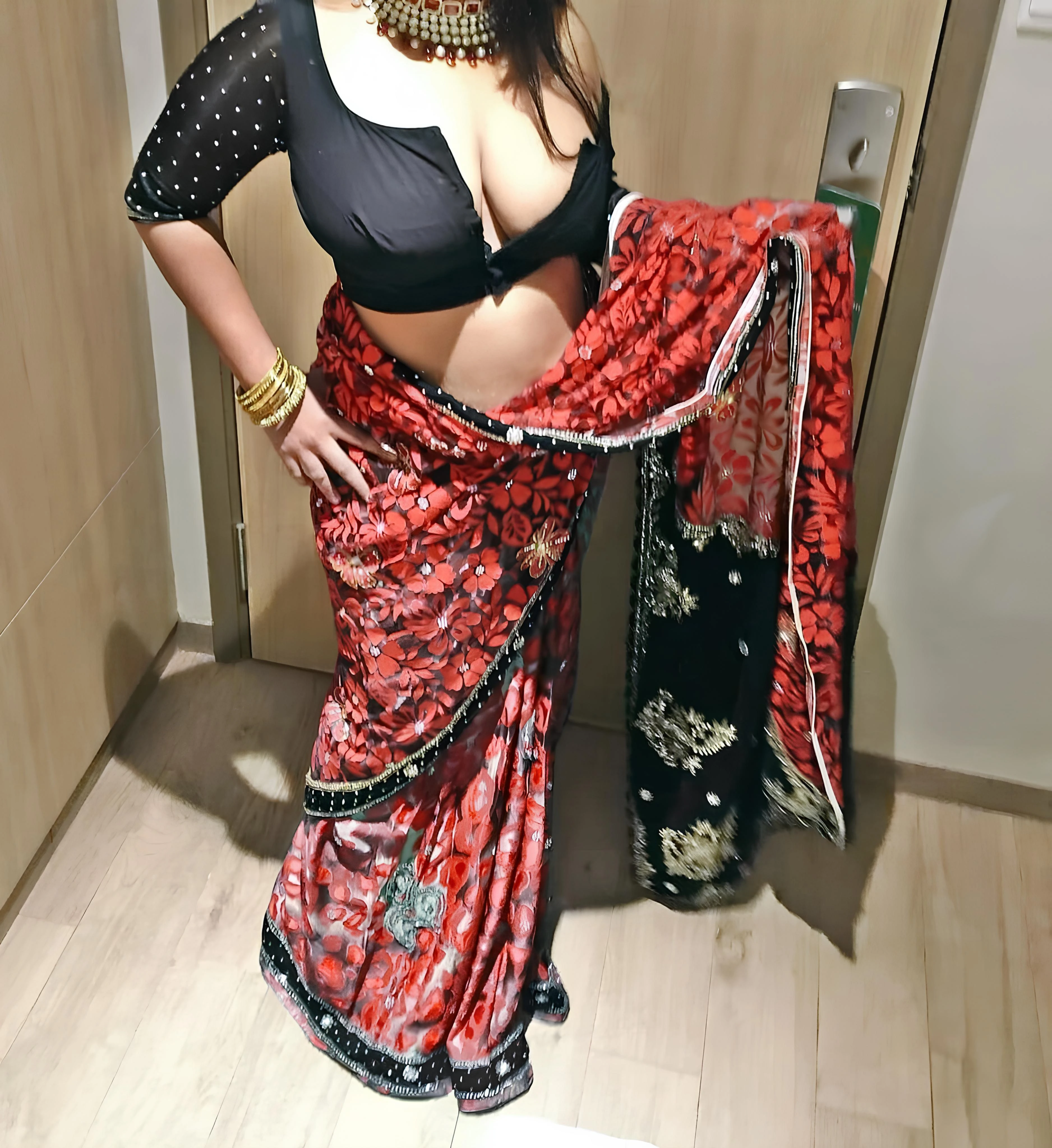 Busty Desi woman in unbuttoned black blouse and red sari exposing her heavy natural breasts in a hallway