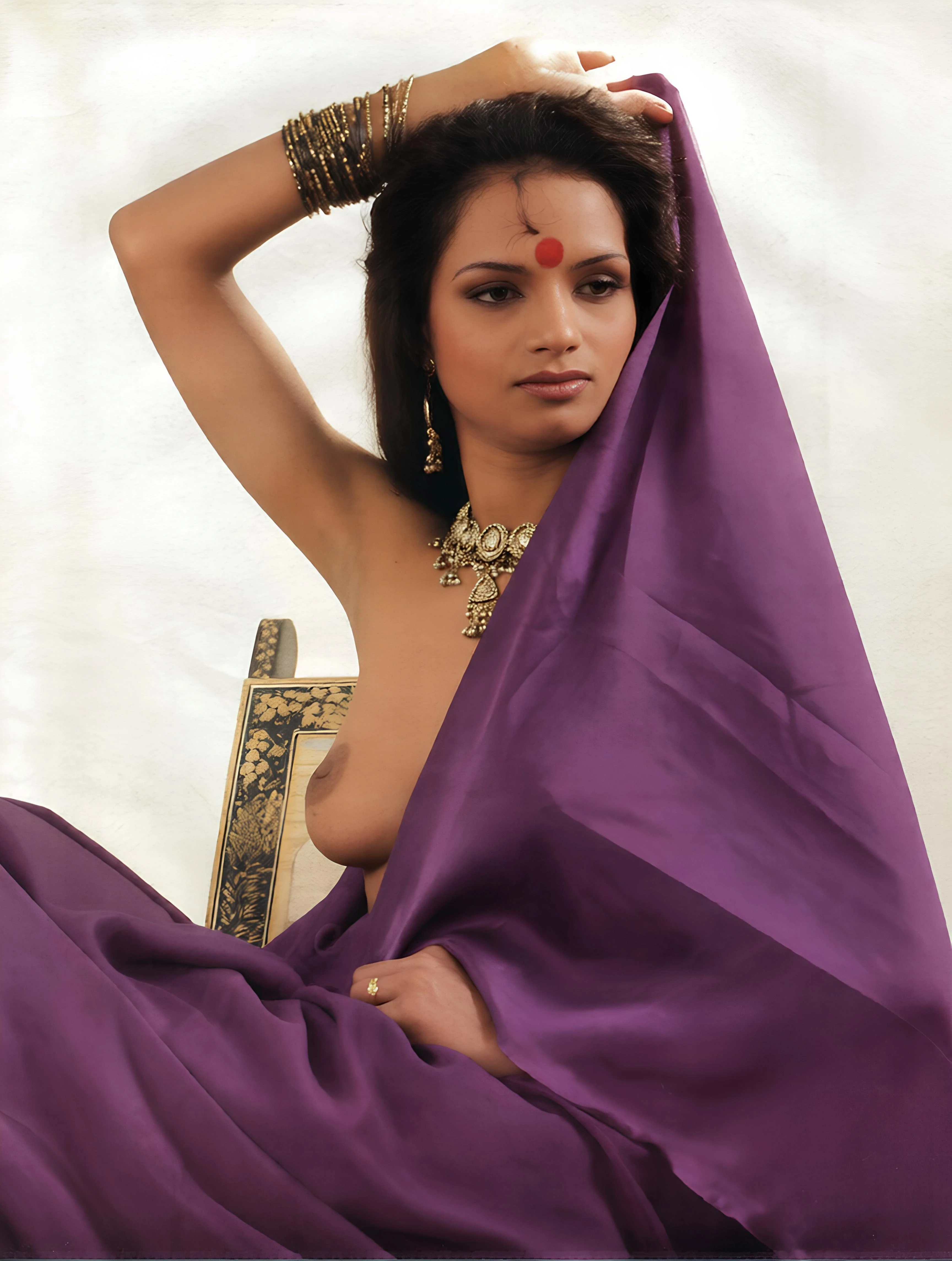 Vintage Desi model adorned in jewelry poses topless with purple saree drape revealing one naked boobs