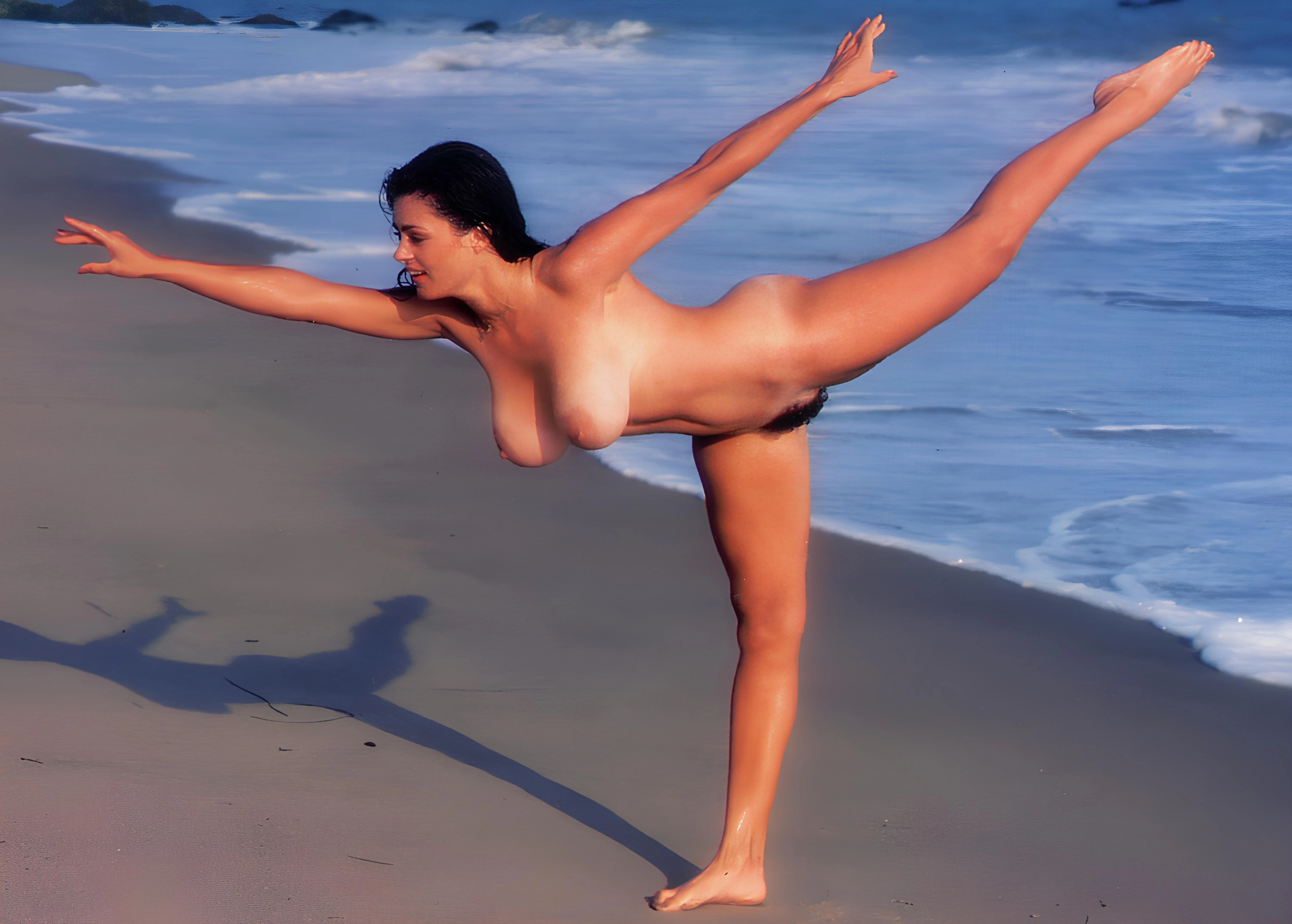 Karen Price performs a nude yoga pose on a sun-drenched beach showing her big boobs and hairy pussy