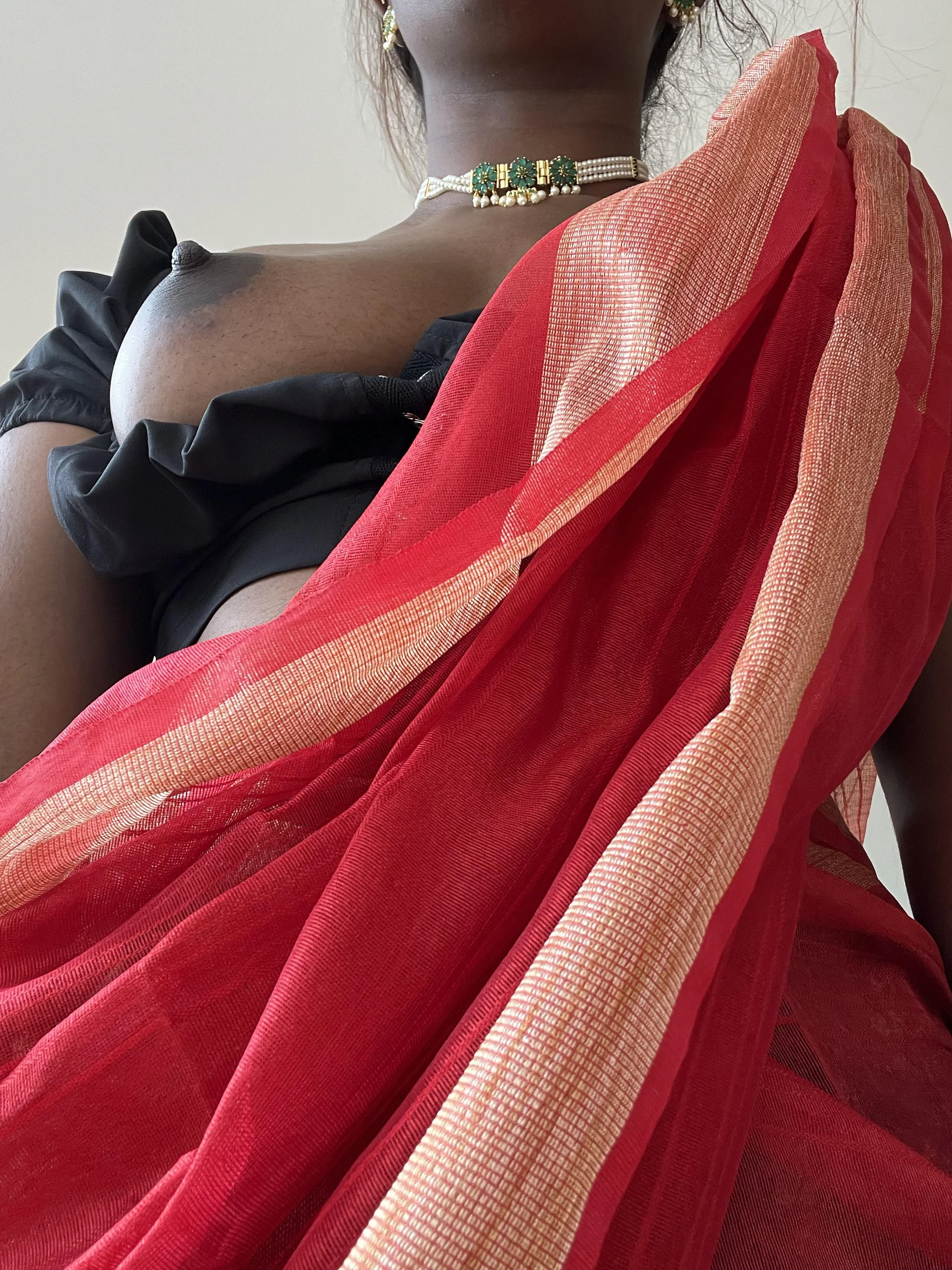 Desi beauty with deep brown skin and full breast showing dark nipple in traditional red saree with gold border