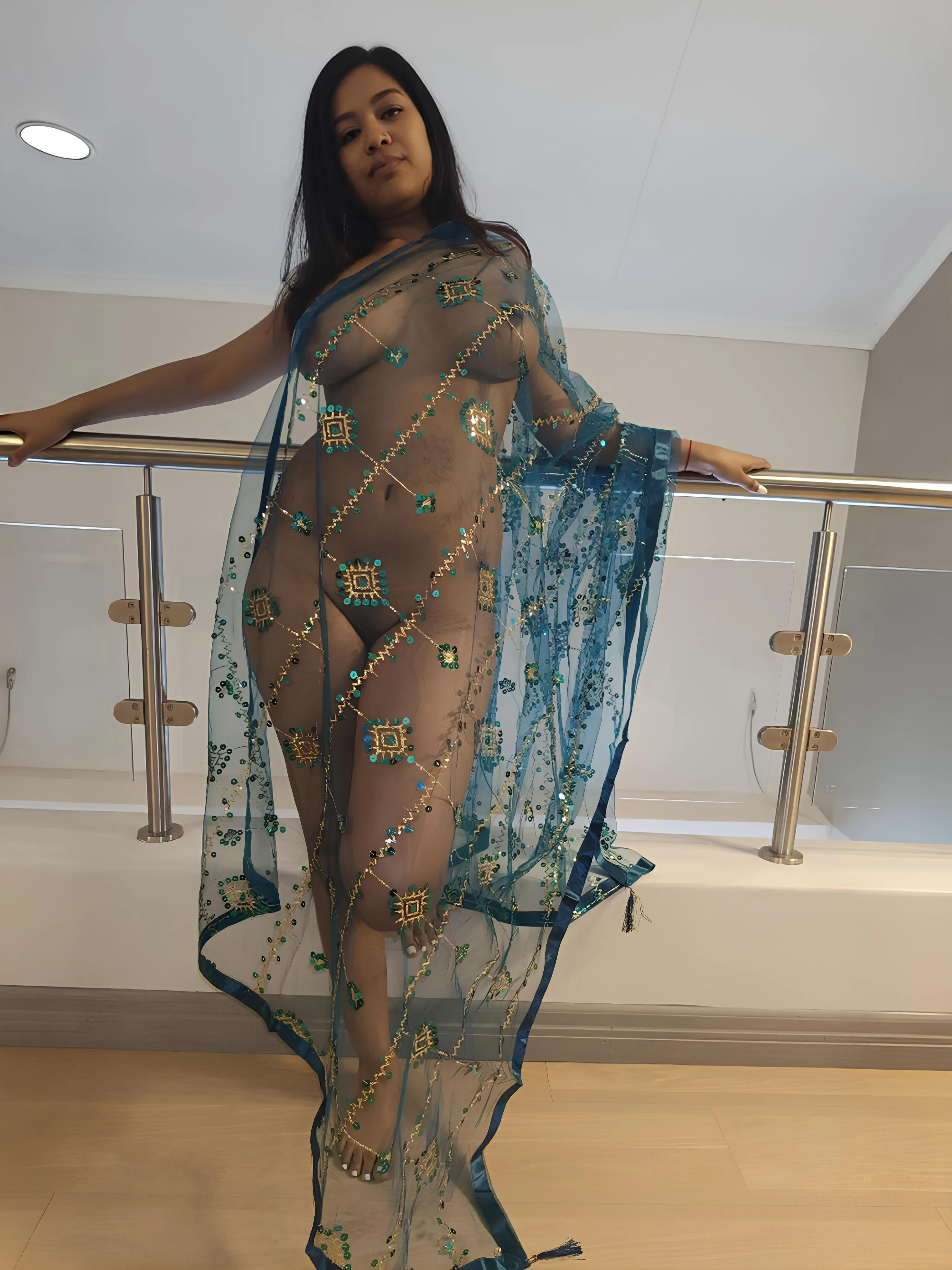 Artistic portrait of Desi woman with bare breasts and pussy through sheer blue braless saree on polished wood with low-angle perspective