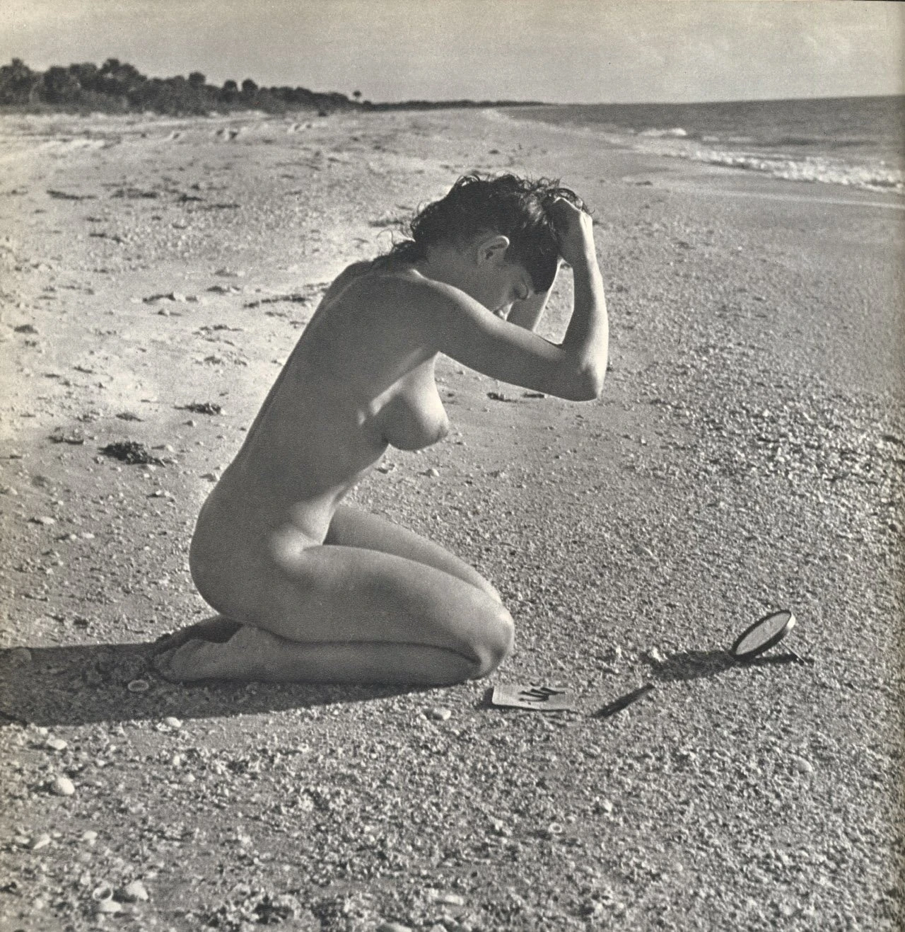 Nude woman with small round breasts kneeling on beach from Lucien Clergue